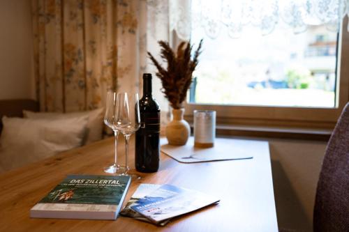 a table with a bottle of wine and a book and glasses at Ferienwohnung Kreidl in Schlitters