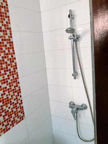 a shower in a bathroom with white tiles at Villa Terracotta - Riviera Synacassi - 3 chambres in Abidjan