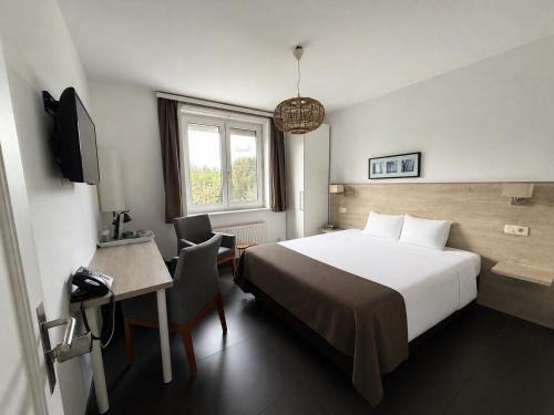 ein Schlafzimmer mit Bett, Schreibtisch und Fernseher in der Unterkunft Lavan in Löwen