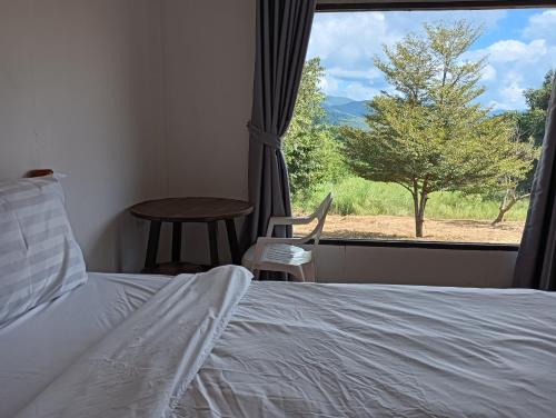 a bedroom with a bed and a window with a view at Pai sunrise camping resort in Pai
