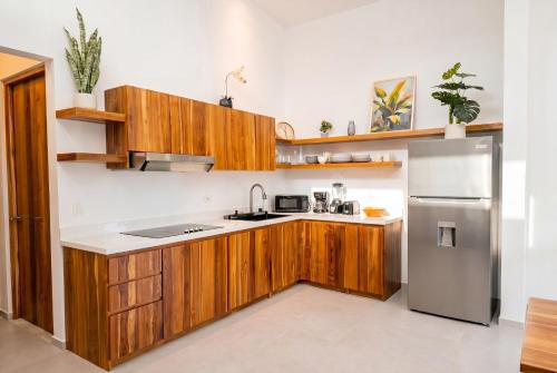 a kitchen with wooden cabinets and a stainless steel refrigerator at Villa Osa Mythica in Puerto Jiménez