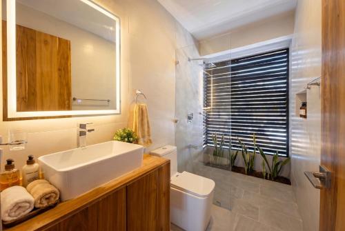 a bathroom with a sink and a toilet and a mirror at Villa Osa Mythica in Puerto Jiménez