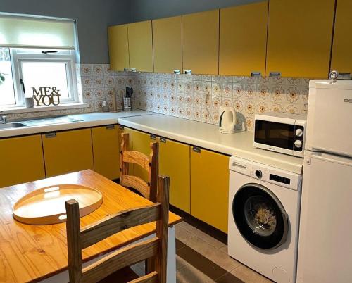 a kitchen with yellow cabinets and a table and a dishwasher at Butterfly cottage in Belmullet
