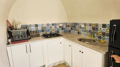a kitchen with a sink and tiles on the wall at Houch traditionnelle in Houmt Souk
