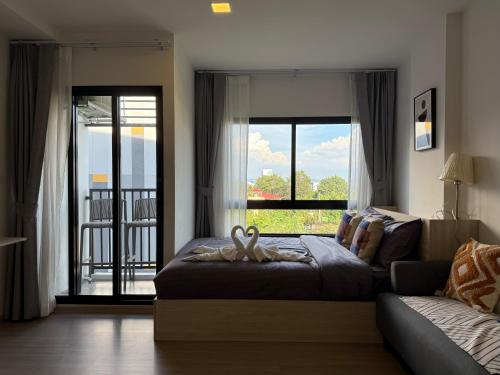 a bedroom with a bed and a couch and a window at Vay Pothisan in North Pattaya