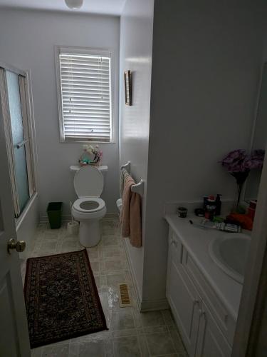 a white bathroom with a toilet and a sink at Masonville Guesthouse in London