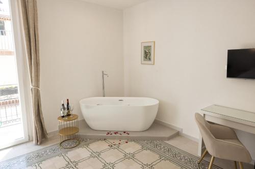 a white bath tub sitting in a bathroom with a desk at Palazzo Sorge - Sicilian Charm in Balestrate