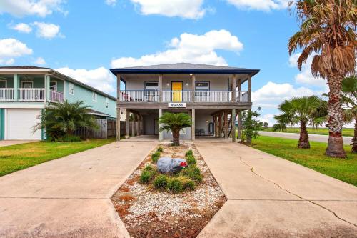 a large house with palm trees and a driveway at Spacious & Pet Friendly - Game Room Sleeps 10 in Port Aransas
