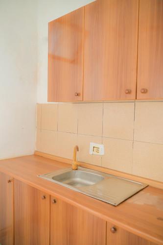 a kitchen counter with a sink and wooden cabinets at Noa Hotel Velipoje in Velipojë