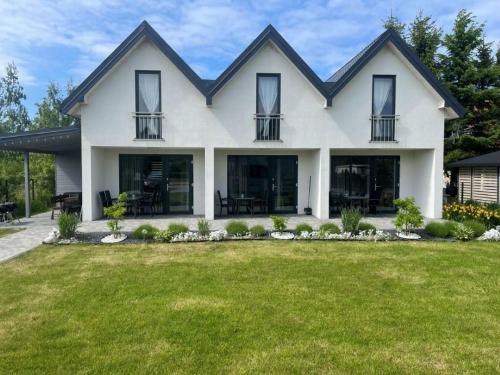 a white house with windows and a yard at Malaga in Gąski