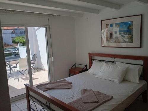 a bedroom with a bed with white sheets and a balcony at Avraam Apartment Polychrono in Polychrono
