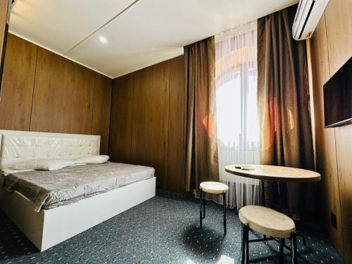 a small bedroom with a bed and two tables at Гостиница Желкен in Aktobe