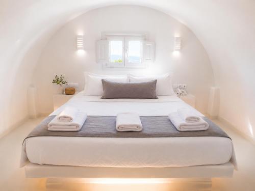 a bedroom with a white bed with towels on it at Perissa Design Centro Suites- BEACH FRONT in Perissa