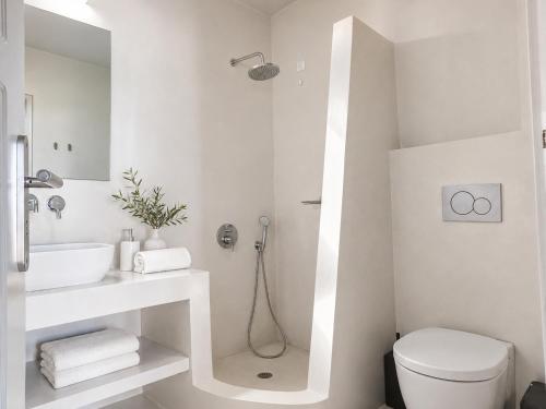 a white bathroom with a sink and a toilet at Perissa Design Centro Suites- BEACH FRONT in Perissa