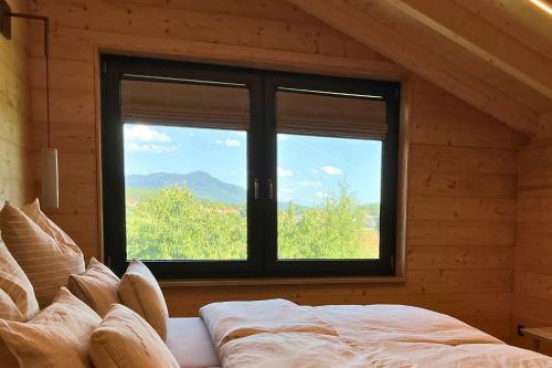 a bedroom with a bed and a window with a view at Bayerwald Chalet Liebenstein in Bad Koetzting