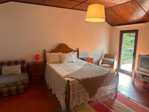 a bedroom with a bed and a chair and a tv at Casa dos Avós in Geres