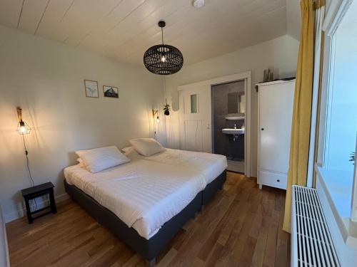 a bedroom with a white bed and a refrigerator at Recreatieappartement BoerdeRijlst - De Winkel in Sint Nicolaasga