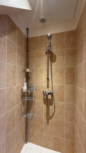 a shower in a bathroom with brown tile at L'Overlord , meublé de tourisme in Colleville-sur-Mer