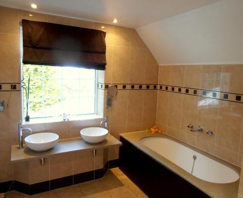 La salle de bains est pourvue de 2 lavabos et d'une baignoire. dans l'établissement The Hunters Rest Inn, à Clutton