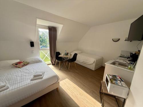 a room with two beds and a table and a sink at L'Overlord , meublé de tourisme in Colleville-sur-Mer