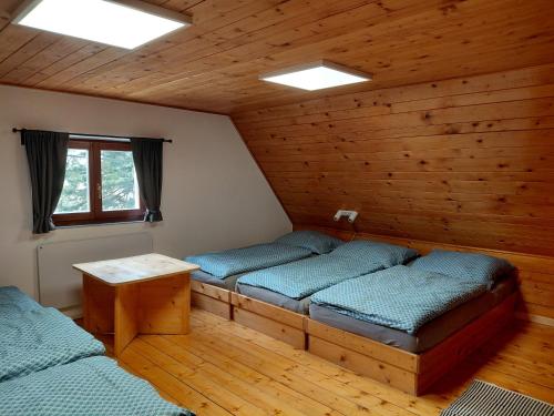 a room with two beds and a table in a cabin at Chata Vedle Jedle in Dolní Morava