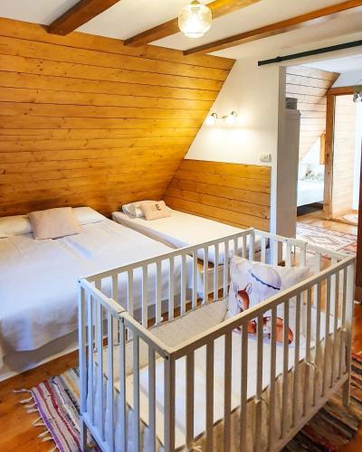 a bedroom with two beds and a crib at Căsuța cu Alune in Rîmeţi-Valea Uzei