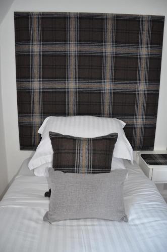 a bed with four pillows and a plaid headboard at Edinburgh37 in Edinburgh