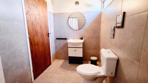 a bathroom with a toilet and a sink and a mirror at La Isolina Chacras, jardín, parrilla y naturaleza! in Chacras de Coria