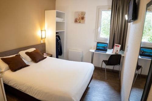 a hotel room with a bed and a desk with a laptop at Fasthôtel Périgueux - Un Hôtel FH Confort in Marsac-sur-lʼIsle