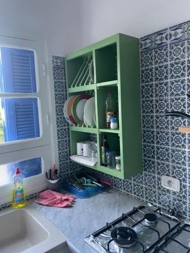 a kitchen with green cabinets and a sink and a stove at SecretVilla in Ghār al Milḩ
