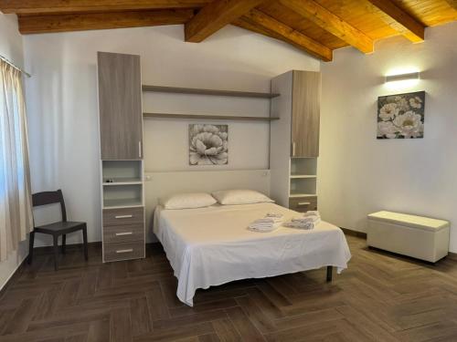 una camera da letto con un letto bianco e una sedia di Madomare Case al Mare a Lampedusa