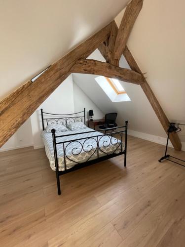 a bedroom with a bed in a attic with wooden floors at Parenthèse au Gué des Archers maison climatisée in Saint-Valérien