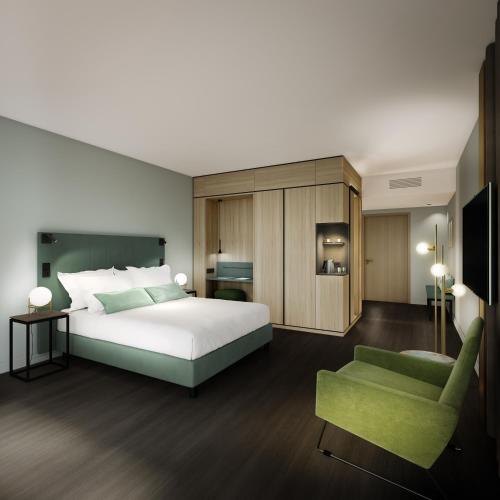 a bedroom with a bed and a green chair at SOLLER Business Hotel - Munich Airport MUC in Hallbergmoos