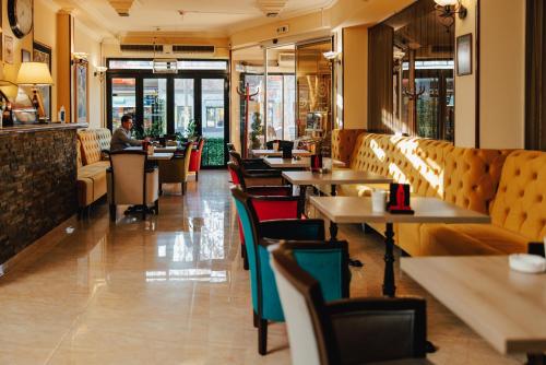 ein Restaurant mit Tischen und Stühlen und einer Person, die an einem Tresen sitzt in der Unterkunft Garni Hotel Planeta Inn in Novi Sad