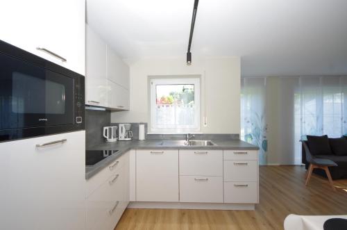 a white kitchen with a sink and a microwave at Ferienwohnung Dorada in Neukirch
