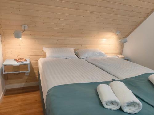 two beds in a bedroom with a wooden wall at Harasiuki House in Harasiuki