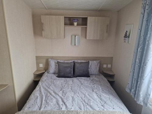 a bed with blue pillows in a small room at Riley's Caravan sand le mere tunstall view in Tunstall