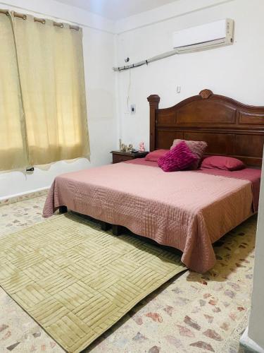 a bedroom with a bed with pink sheets and a rug at Casa céntrica en Paraíso Amplia y cómoda in Paraíso