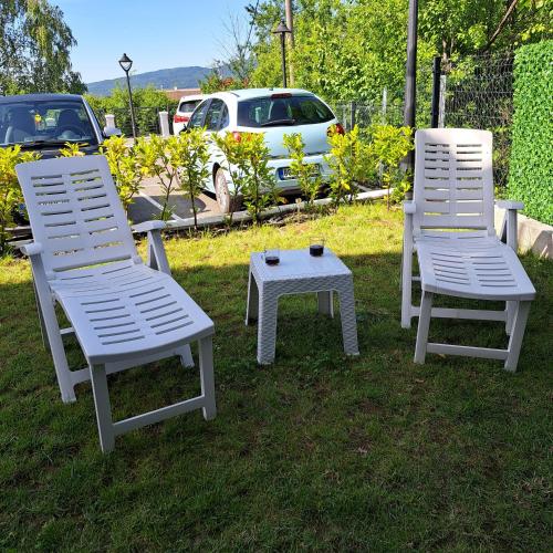 two white chairs and a table in the grass at Ljubičica deluxe 2 - Novo - Privatno dvorište - Parking in Vrnjačka Banja