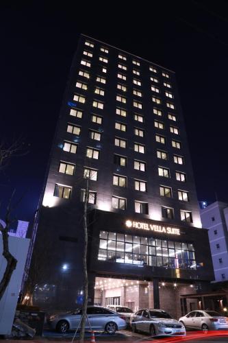 un bâtiment d'hôtel avec des voitures garées devant lui dans l'établissement Vella Suite Hotel, à Suwon