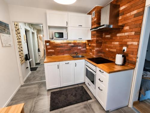 a kitchen with white cabinets and a brick wall at RosalieRose Cozy Corner in Radom