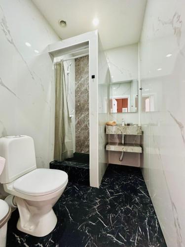 a white bathroom with a toilet and a shower at Гостиница Желкен in Aktobe