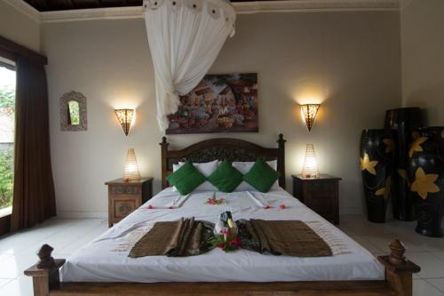 a bedroom with a bed with white sheets and green pillows at Villa Anjing in Nusa Dua