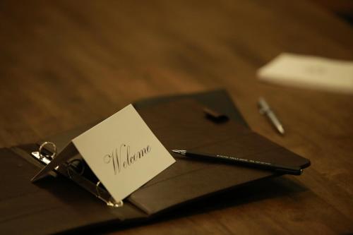 a notebook with a note and a pen on a table at Vella Suite Hotel in Suwon