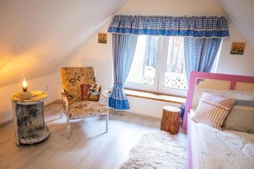 a bedroom with a bed and a chair and a window at Valašská chalupa Červenka in Lužná