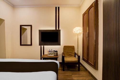 a bedroom with a bed and a chair and a television at Collection O Lake Mall Kalighat Formerly Venkateshwara in Kolkata