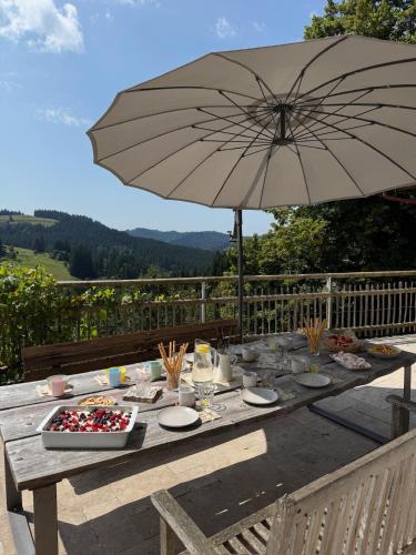 a picnic table with an umbrella on a deck at Alpe Sonnenruh in Buchenberg