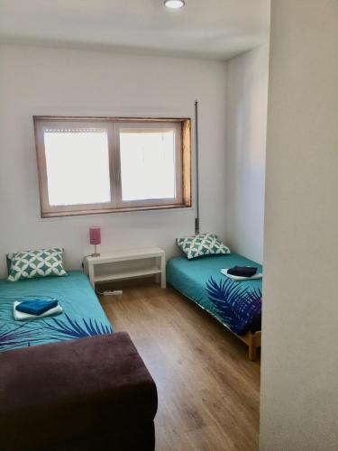two beds in a small room with a window at CALIFORNIA dream in Peniche