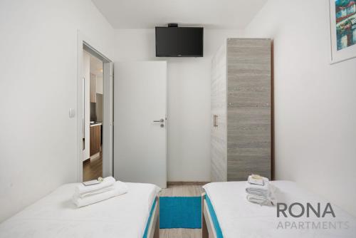 two beds in a room with a tv on the wall at Rona Apartments Zlatko in Šimuni