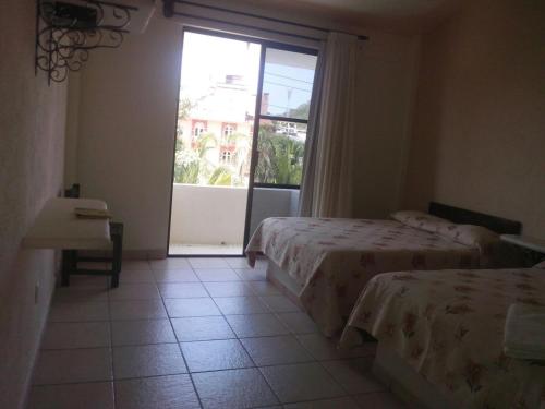 a bedroom with two beds and a large window at Balcon Gueela in Santa Cruz Huatulco